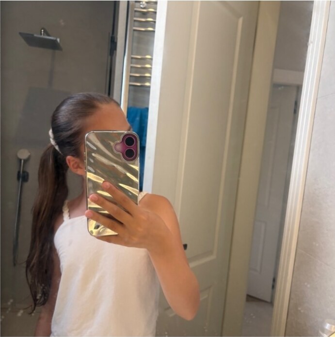 Nina sa sjajnom maskom telefona fotografisana u ogledalu